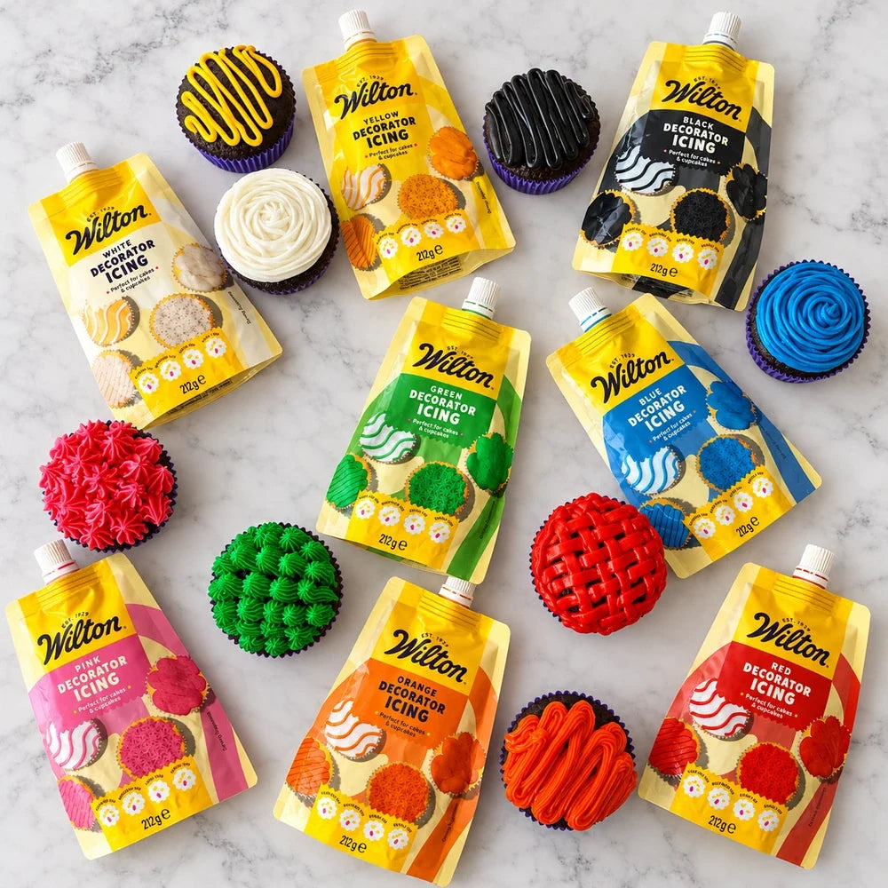Wilton ferdig frosting i flere farger med dekorerte cupcakes på lys marmor