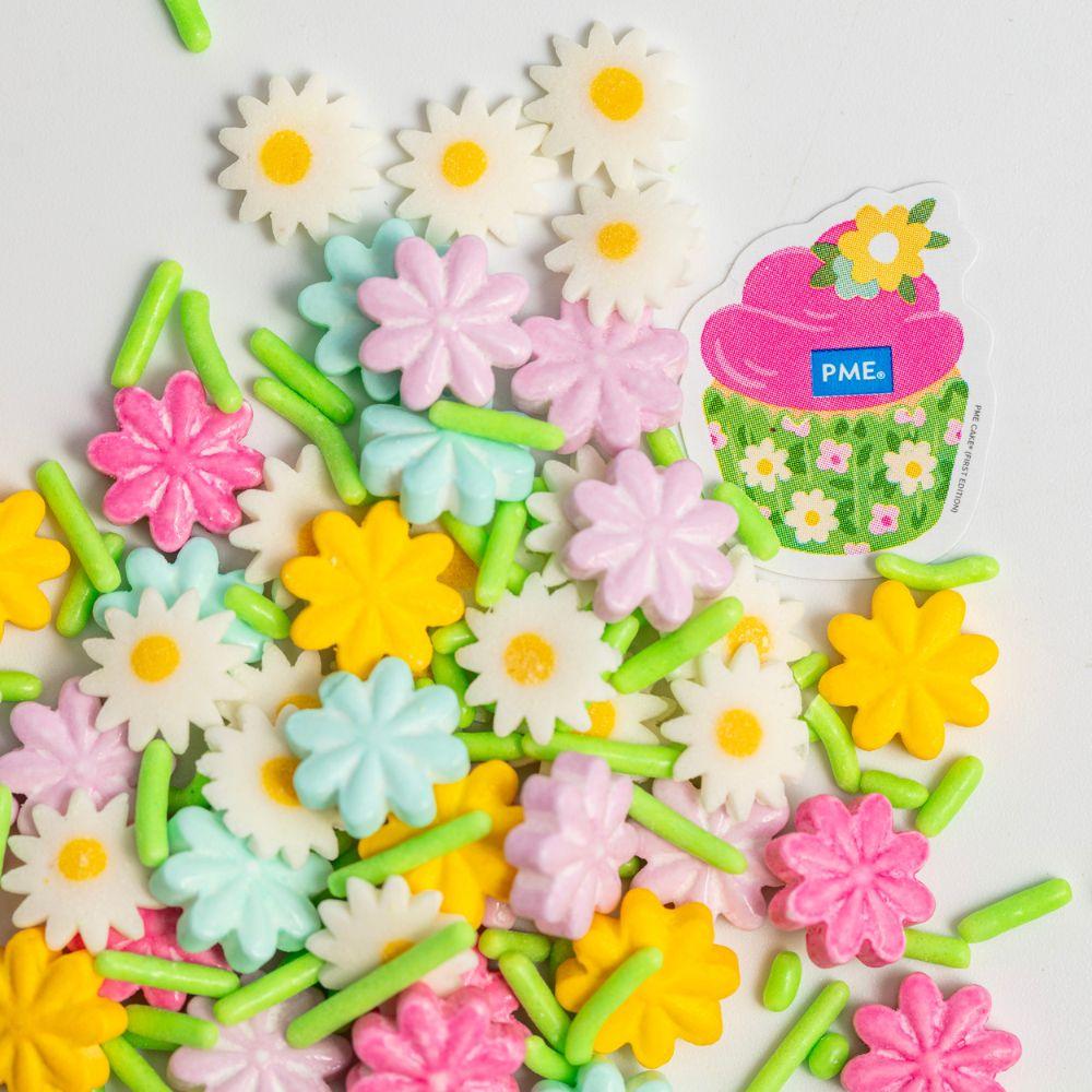Nærbilde av kakestrøssel med blomsterformet konfetti og jimmies i pastellfarger