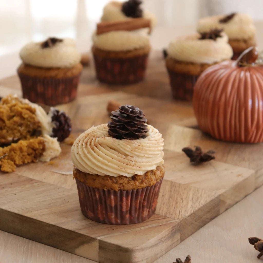 Cupcake pyntet med en FunCakes sjokoladekongle med et dekorativt gresskar i bakgrunnen