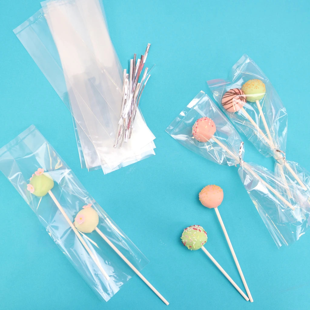 Cake pops og gjennomsiktige poser med sølvbånd på blå bakgrunn