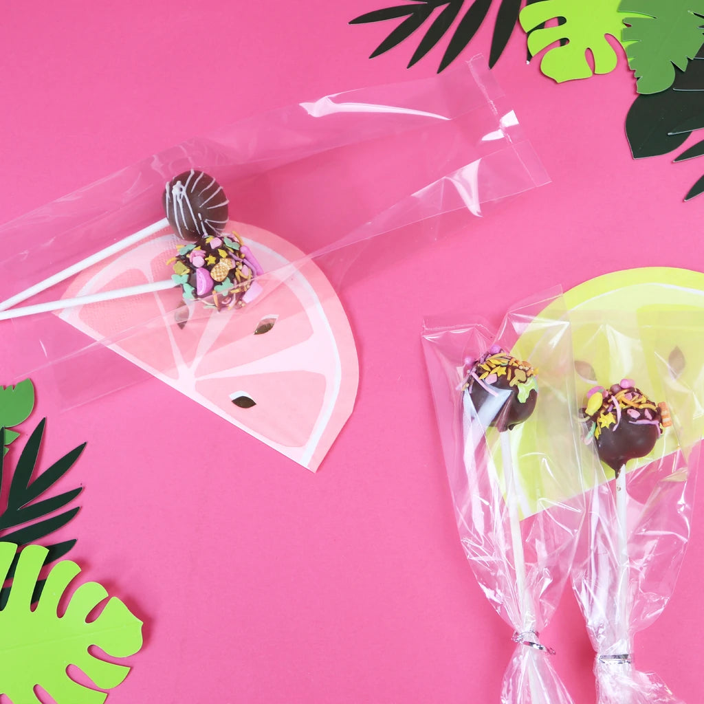 Ferdigpakkede cake pops i gjennomsiktige poser på rosa bord
