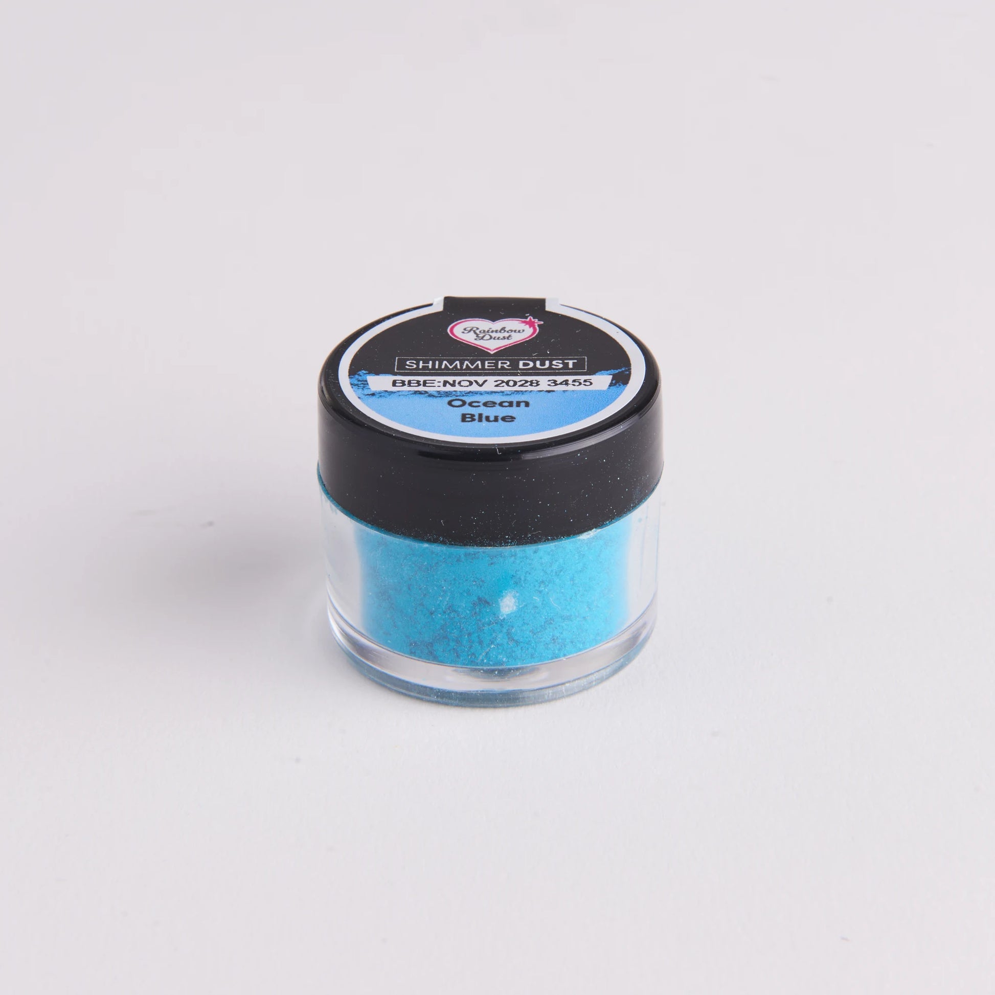 Rainbow Dust Shimmer Dust Ocean Blue – liten krukke med svart lokk og hengekortet, sett skrått