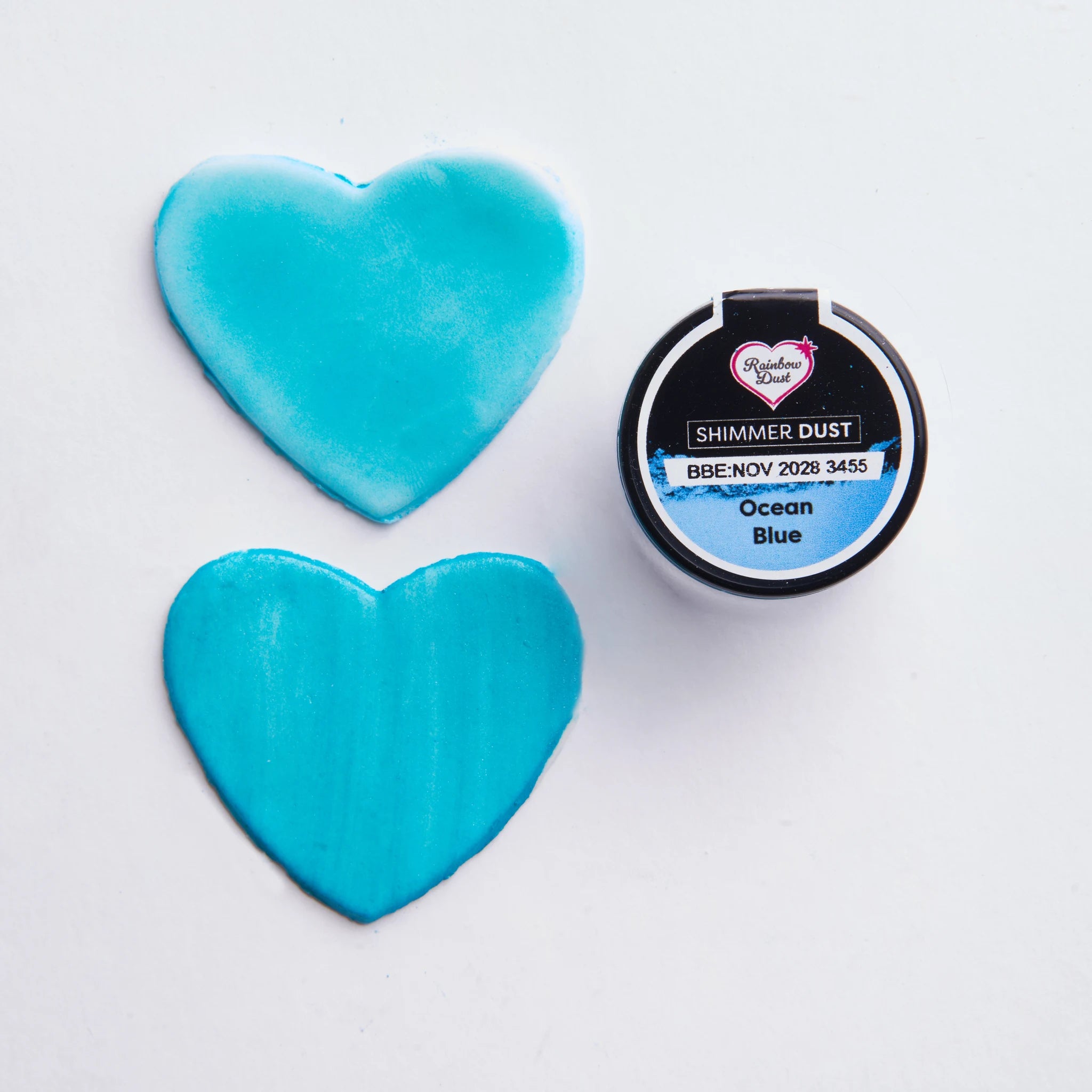 Rainbow Dust Shimmer Dust Ocean Blue påført på hjerteformer – lett og kraftig påføring sammenlignet