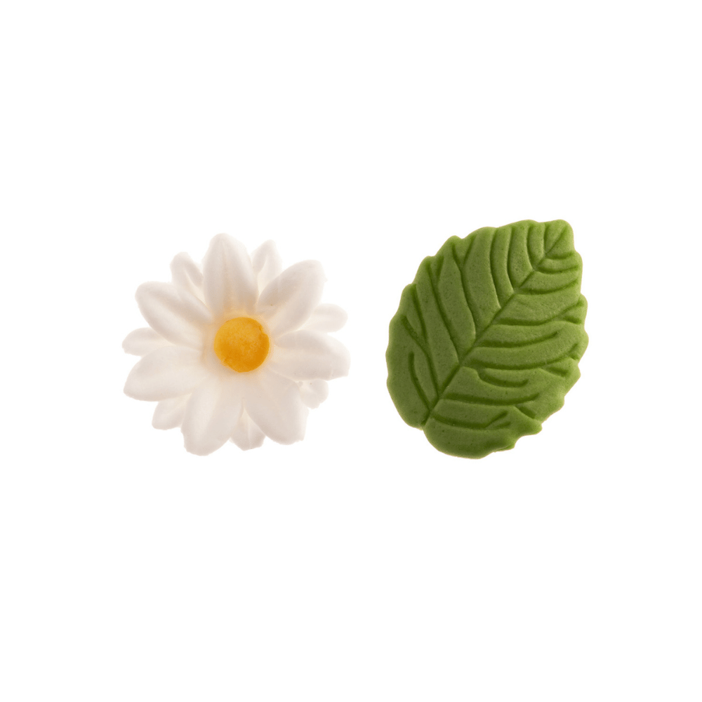 Nærbilde av spiselig kakepynt hvite margeritter med gult sentrum og grønne blad