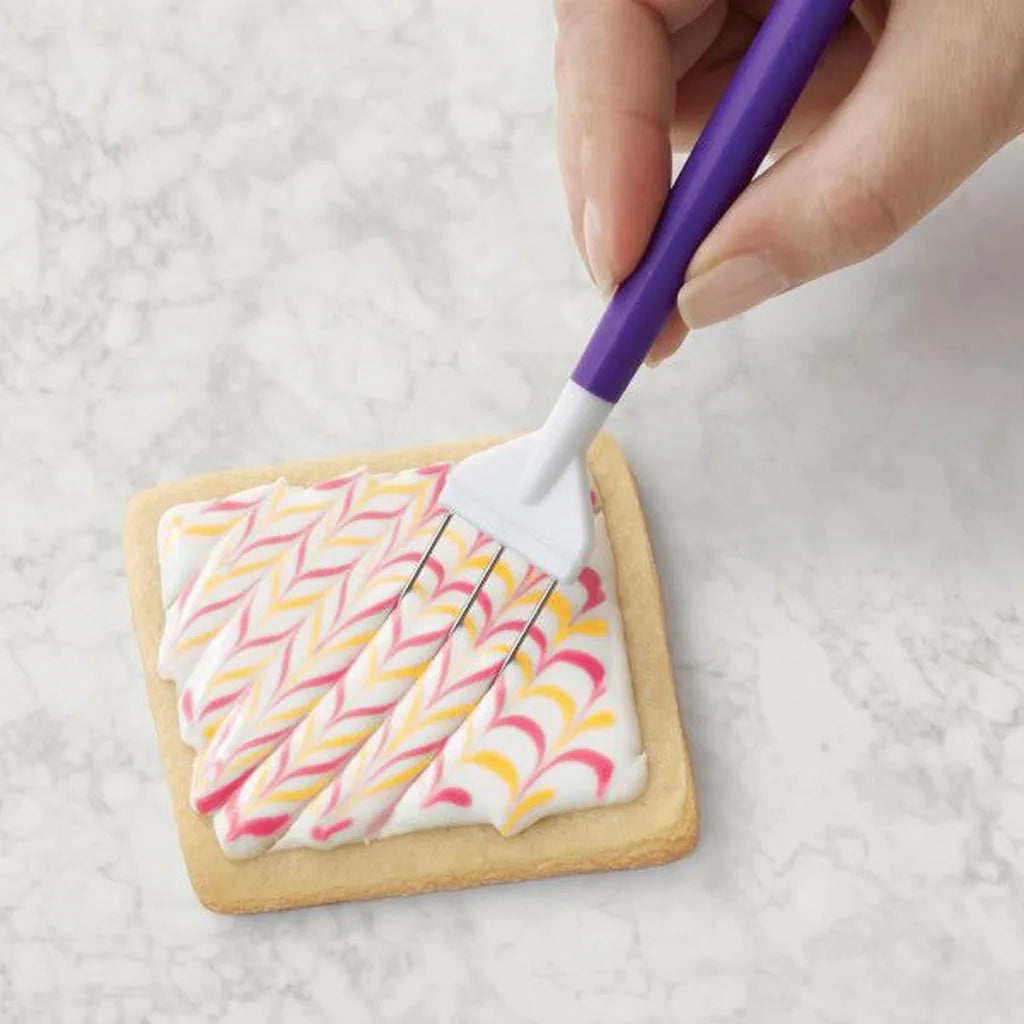 Wilton kamverktøy brukt til feathering-mønster i royal icing